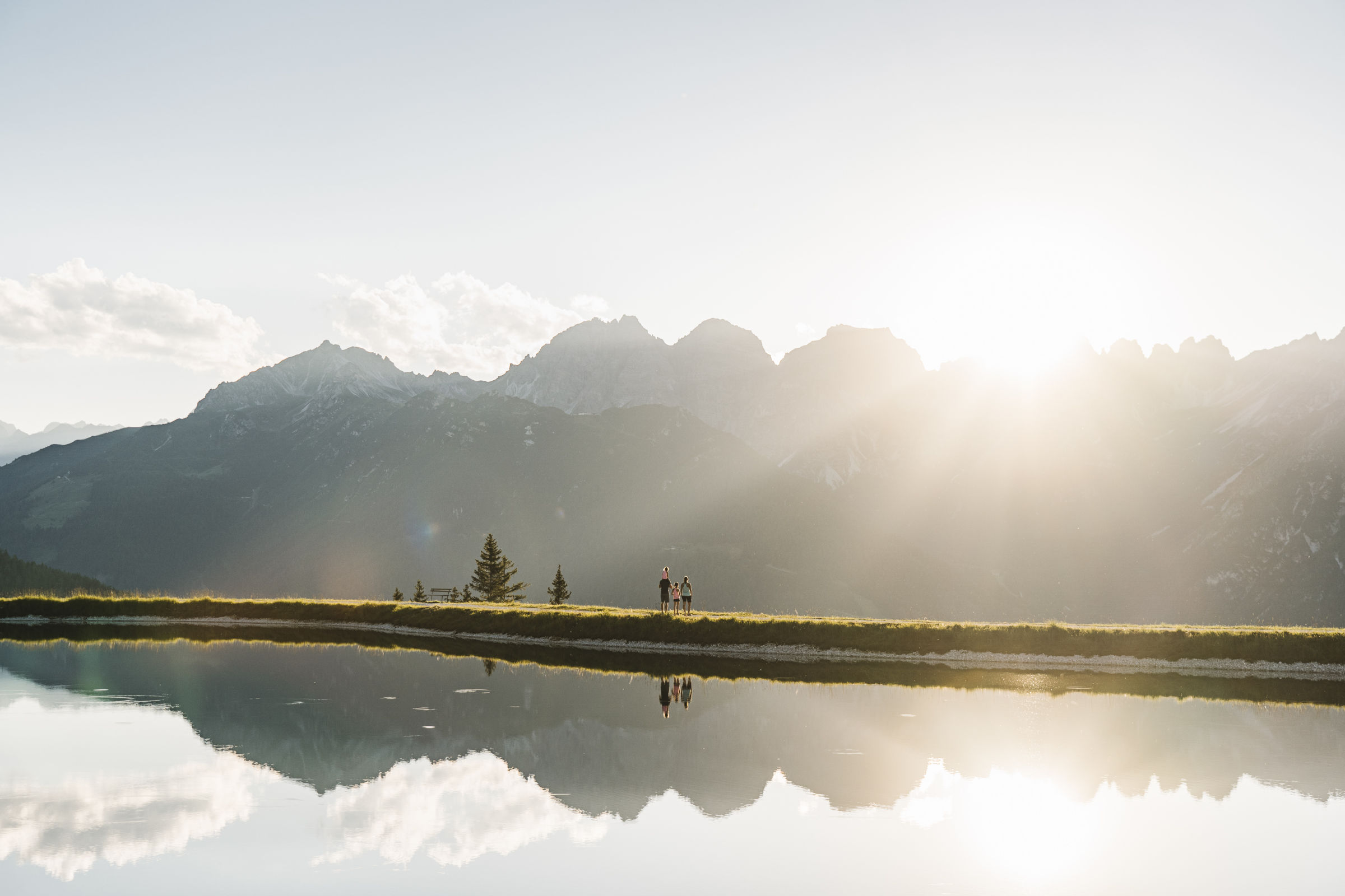 Familie mit Kindern genießt die Abendsonne an einem Bergsee inmitten der Stubaier Bergwelt – gemeinsame Familienabenteuer im Sommerurlaub im Stubaital